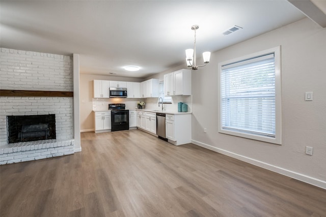 kitchen with wood finished floors, a sink, white cabinets, light countertops, and appliances with stainless steel finishes