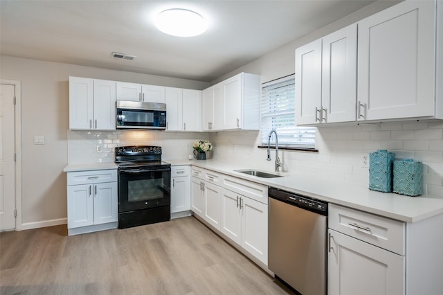 kitchen featuring visible vents, white cabinets, appliances with stainless steel finishes, light wood-style floors, and a sink