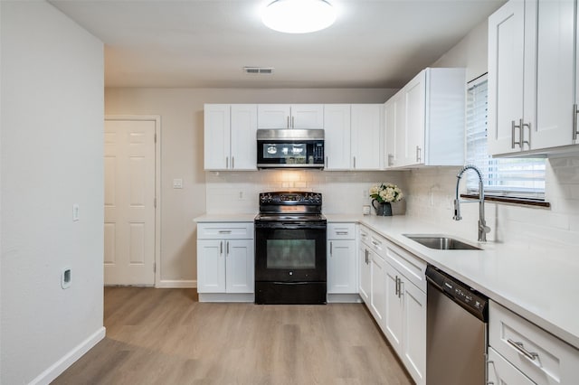 kitchen with stainless steel appliances, light countertops, light wood-style floors, white cabinetry, and a sink