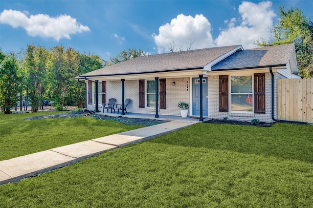 ranch-style house featuring covered porch, brick siding, a shingled roof, fence, and a front yard