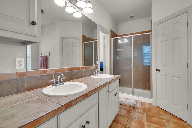 full bath with tile patterned floors, a shower stall, double vanity, and a sink