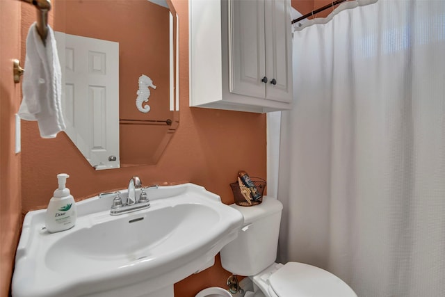 bathroom with a sink, curtained shower, and toilet