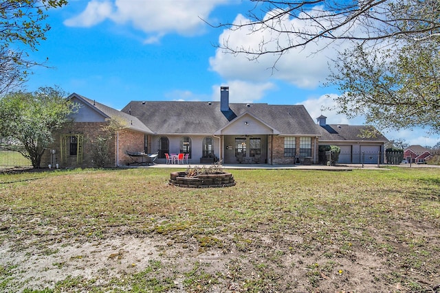 rear view of house featuring a yard, a fire pit, an attached garage, and a patio area