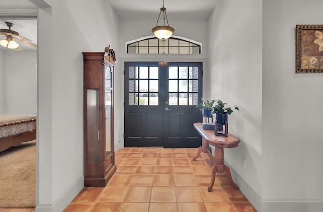 tiled entrance foyer with ceiling fan and baseboards