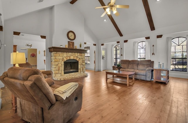 living room featuring beam ceiling, high vaulted ceiling, light wood-style flooring, a ceiling fan, and a fireplace