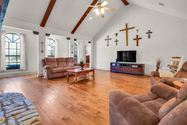 living area featuring light wood-type flooring, high vaulted ceiling, beamed ceiling, and visible vents