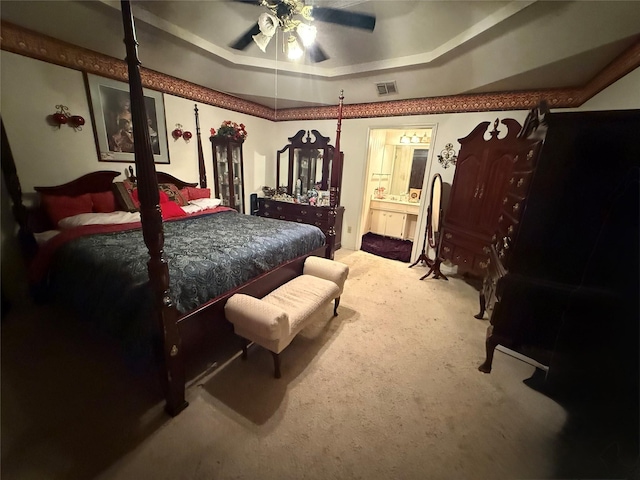 bedroom featuring ensuite bathroom, ceiling fan, carpet floors, visible vents, and a tray ceiling