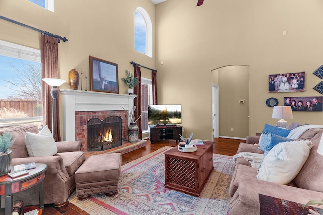 living room with a brick fireplace, plenty of natural light, and arched walkways