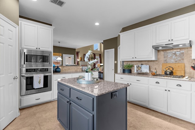 kitchen featuring visible vents, a kitchen island, stainless steel appliances, white cabinets, and under cabinet range hood