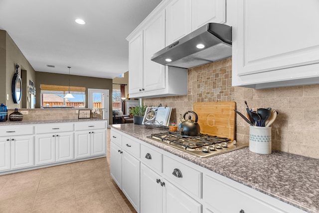 kitchen with tasteful backsplash, range hood, stainless steel gas stovetop, white cabinets, and light tile patterned floors