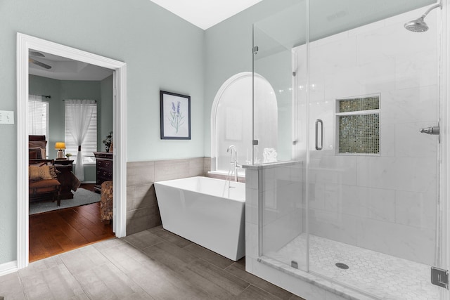 ensuite bathroom featuring connected bathroom, a stall shower, tile walls, and wood finish floors