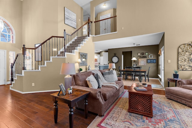 living area featuring baseboards, a high ceiling, stairs, and hardwood / wood-style flooring