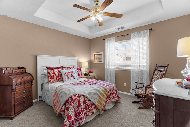 bedroom featuring light carpet, visible vents, baseboards, and a tray ceiling