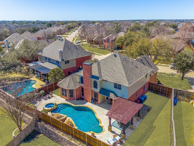 exterior space featuring a patio, a fenced backyard, a residential view, and a pool with connected hot tub