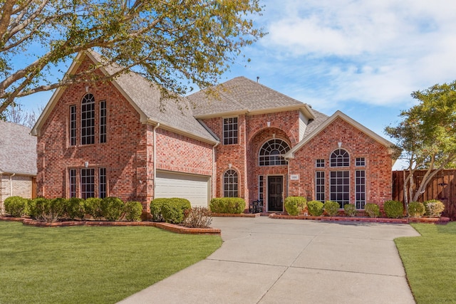 traditional-style house with brick siding, driveway, a shingled roof, and a front yard