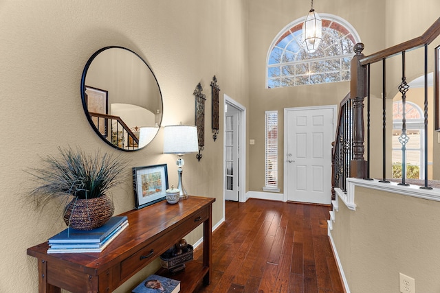 entrance foyer featuring stairway, baseboards, hardwood / wood-style floors, and a towering ceiling