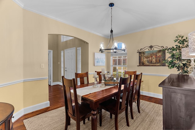 dining area with baseboards, wood finished floors, arched walkways, and ornamental molding