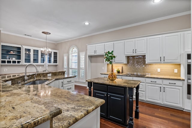 kitchen featuring visible vents, white cabinets, dark wood finished floors, a kitchen island, and a sink