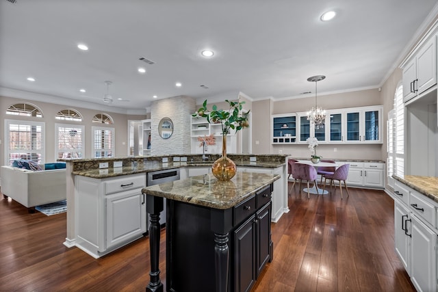 kitchen featuring a breakfast bar area, ornamental molding, dark wood-type flooring, a center island, and white cabinetry