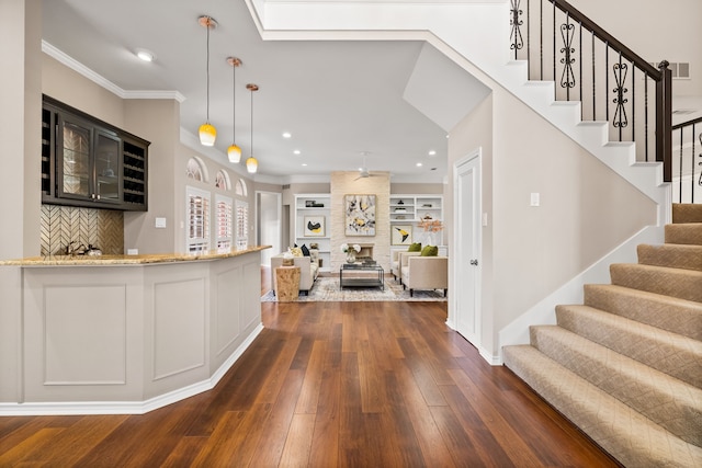 interior space with glass insert cabinets, dark wood-type flooring, open floor plan, ornamental molding, and light stone counters