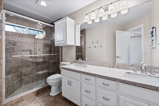 full bath with toilet, a shower stall, double vanity, and a sink