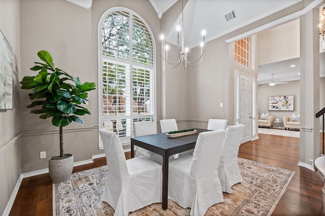 dining area with a towering ceiling, hardwood / wood-style flooring, visible vents, and crown molding