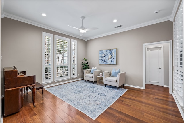 sitting room with ceiling fan, visible vents, dark wood finished floors, and ornamental molding