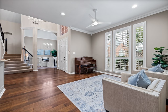 living room featuring baseboards, visible vents, wood finished floors, stairs, and ceiling fan with notable chandelier