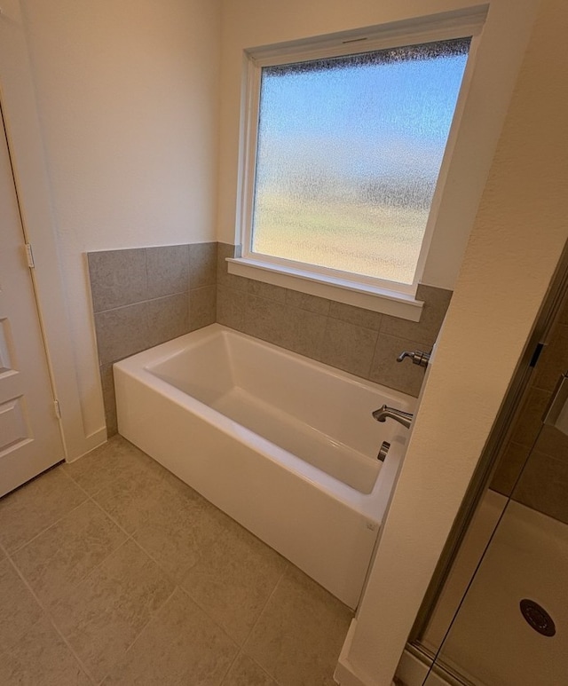 bathroom with a bath, a shower stall, and tile patterned floors