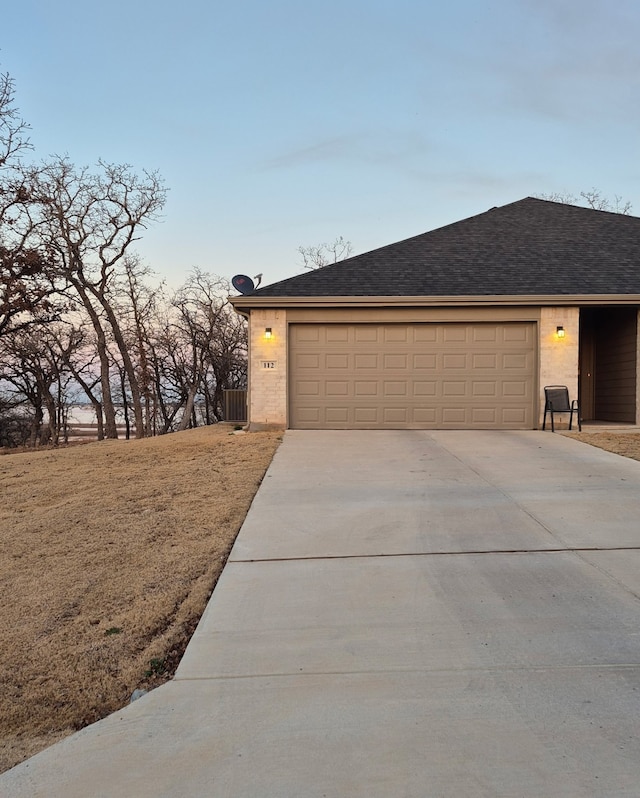 exterior space featuring brick siding, driveway, a garage, and roof with shingles