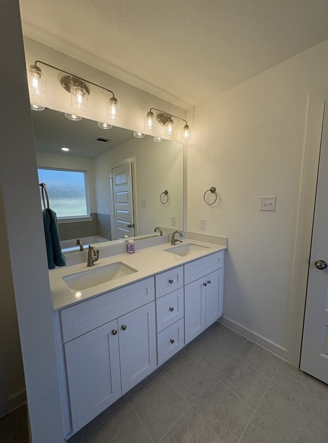 bathroom with double vanity, baseboards, tile patterned floors, and a sink