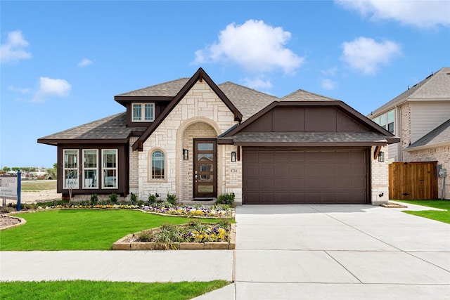 french provincial home featuring driveway, a garage, a shingled roof, a front lawn, and brick siding