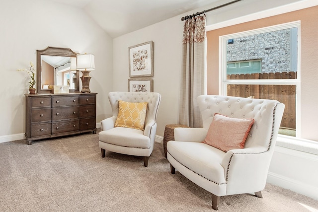 sitting room featuring light colored carpet, vaulted ceiling, and baseboards