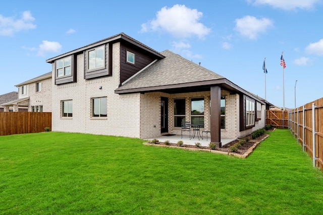 back of house with a patio, brick siding, a lawn, and a fenced backyard