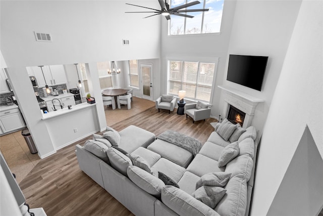 living area with visible vents, a warm lit fireplace, and light wood-style floors