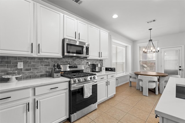 kitchen with tasteful backsplash, light countertops, light tile patterned floors, stainless steel appliances, and white cabinetry