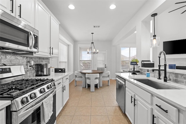 kitchen featuring light countertops, light tile patterned floors, appliances with stainless steel finishes, white cabinetry, and a sink