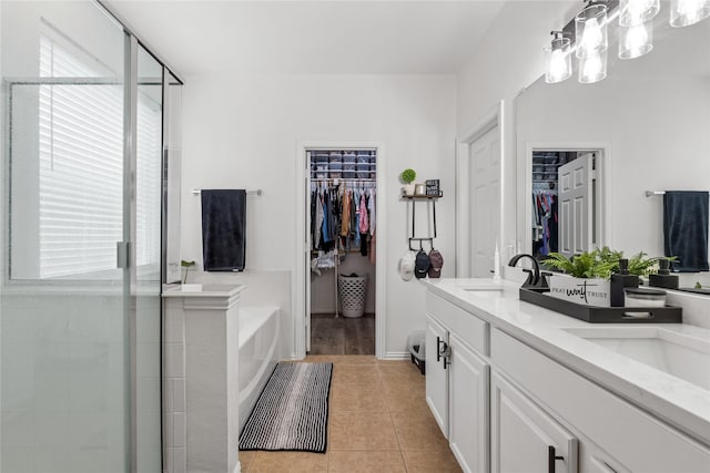 full bathroom featuring a stall shower, a sink, tile patterned flooring, a spacious closet, and a bath