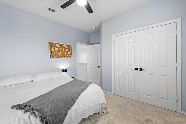 bedroom with ceiling fan, visible vents, a closet, and light carpet