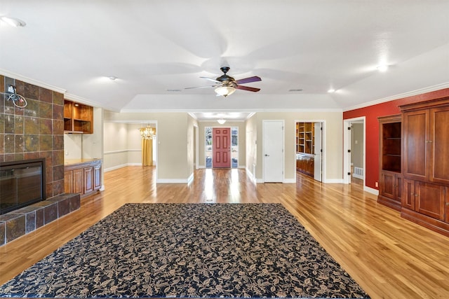 living room featuring visible vents, ornamental molding, a tile fireplace, and light wood-style flooring