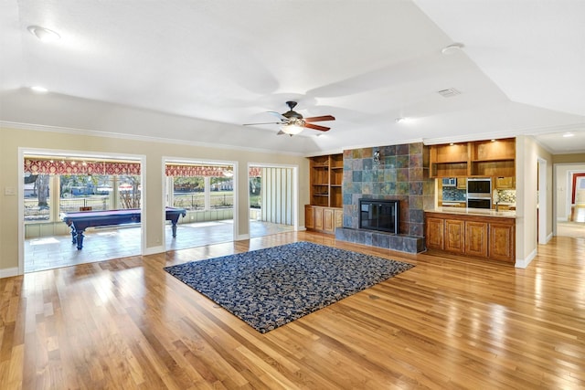 unfurnished living room with a fireplace, crown molding, light wood finished floors, pool table, and ceiling fan