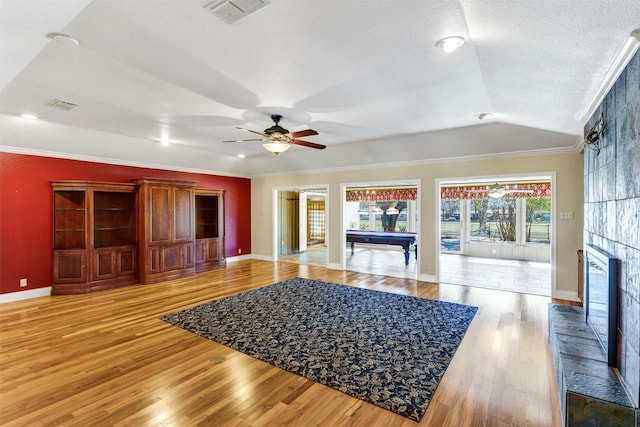 living room featuring light wood-style flooring, crown molding, and a tile fireplace