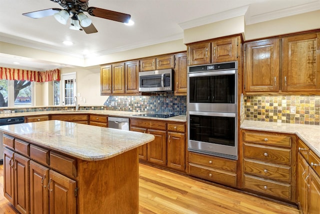 kitchen with brown cabinets, light wood finished floors, stainless steel appliances, and a sink