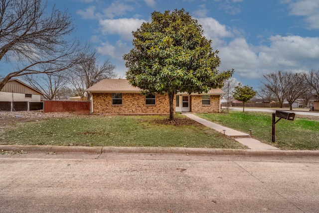 view of front of property with a front yard, brick siding, and fence