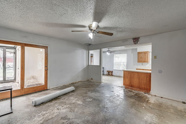 interior space with a ceiling fan, a textured ceiling, and unfinished concrete floors