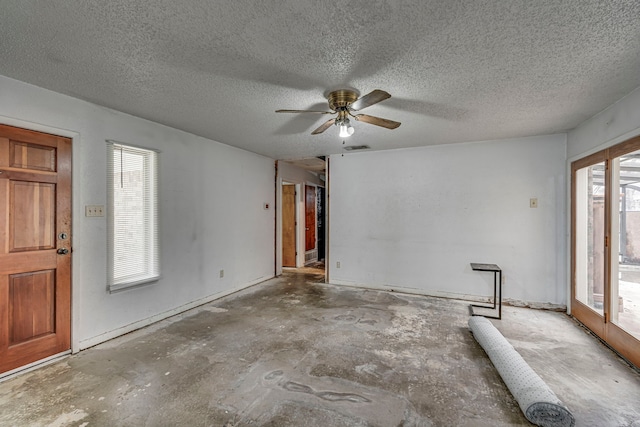 spare room with ceiling fan, concrete floors, a textured ceiling, and visible vents