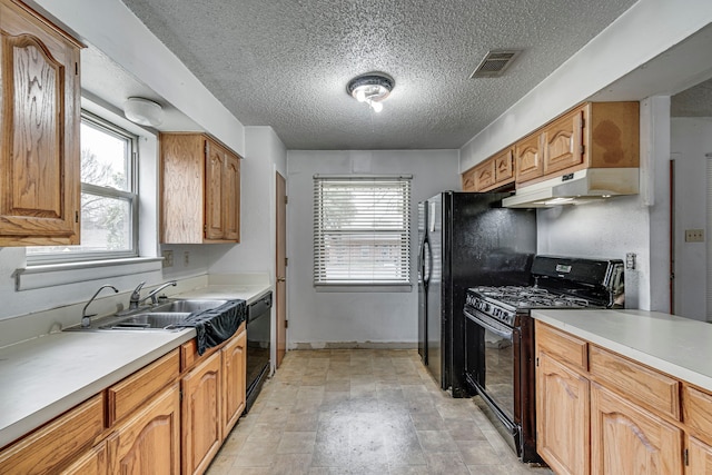 kitchen featuring visible vents, under cabinet range hood, light countertops, black appliances, and a sink