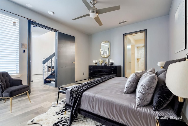 bedroom featuring light wood finished floors, visible vents, and a ceiling fan