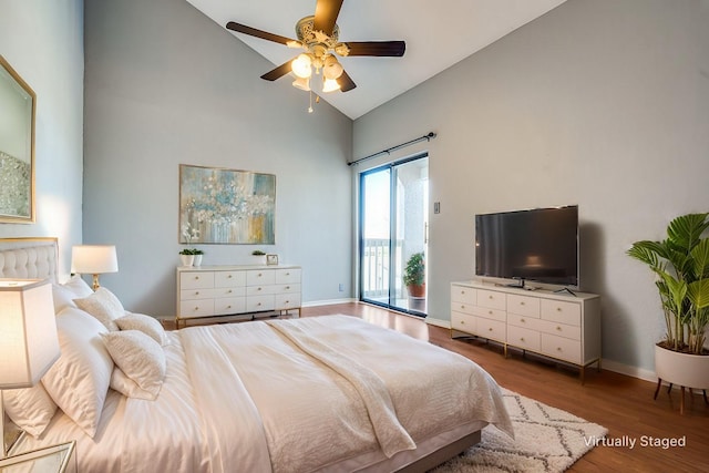 bedroom with access to exterior, high vaulted ceiling, baseboards, and wood finished floors