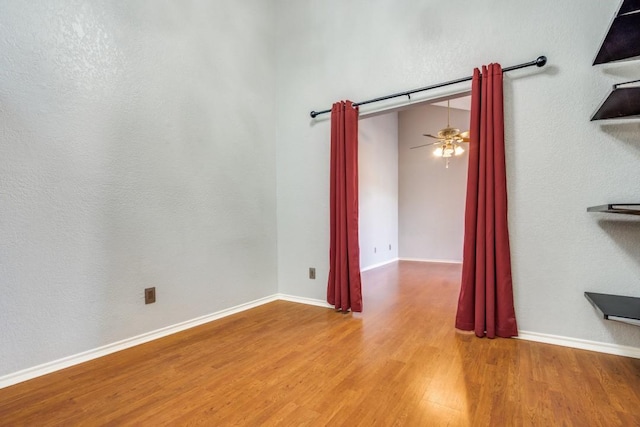 spare room with a ceiling fan, baseboards, and wood finished floors